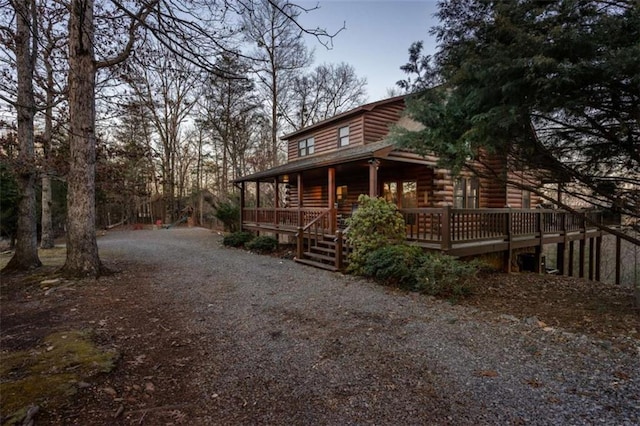 view of side of home with gravel driveway and a porch