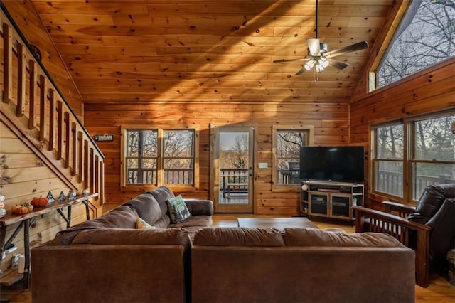 living area with stairs, wooden walls, wood ceiling, and ceiling fan