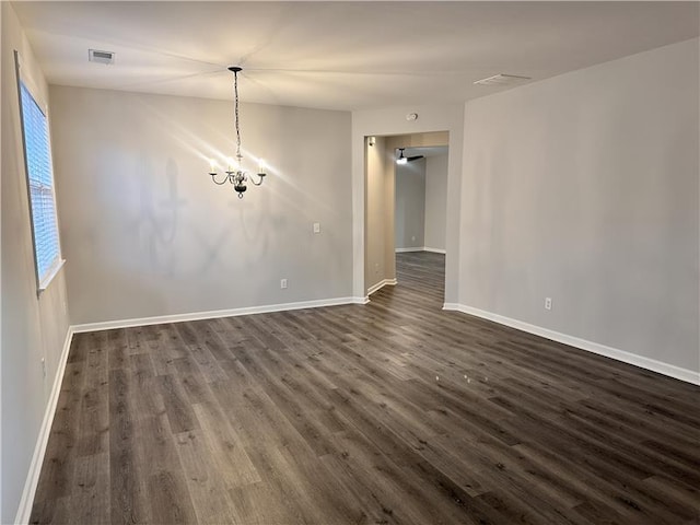 spare room featuring dark hardwood / wood-style floors and a chandelier