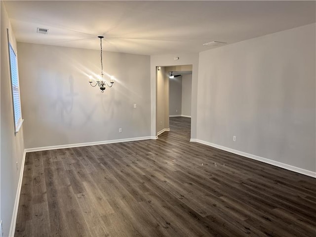 empty room with an inviting chandelier and dark hardwood / wood-style floors