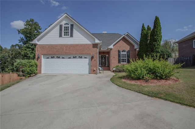 view of front of house with a garage, driveway, brick siding, and fence