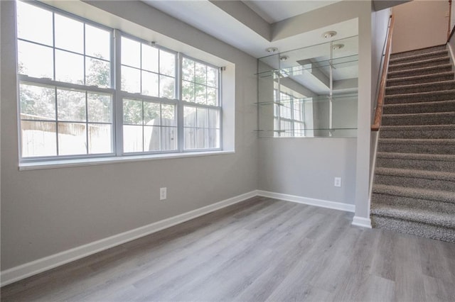 unfurnished room featuring stairs, baseboards, and wood finished floors