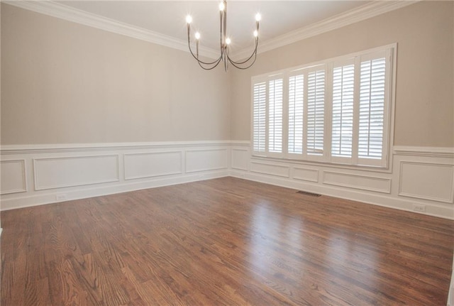 spare room featuring crown molding, wood finished floors, visible vents, and an inviting chandelier