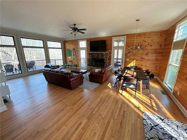 living room with a fireplace, wood-type flooring, ceiling fan, and wood walls