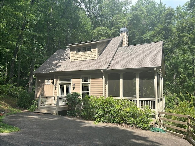 57 Shaggy Maple Ln, Big Canoe, GA 30143 - view of front facade with roof with shingles, a sunroom, a chimney, and a view of trees