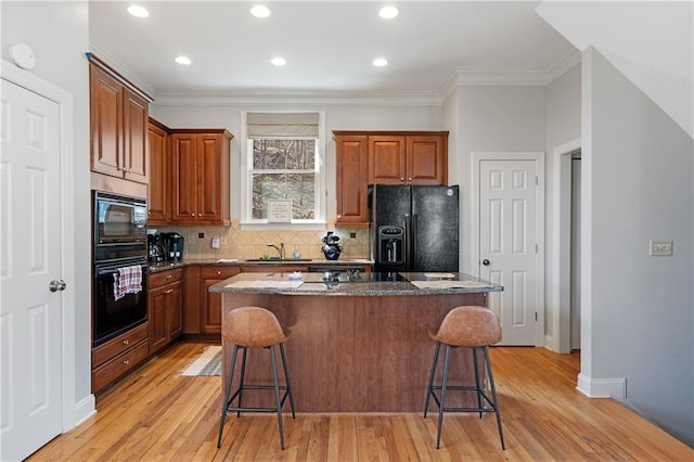 kitchen featuring black appliances, a kitchen island, a kitchen breakfast bar, and a sink