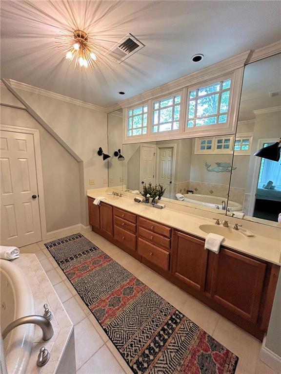 bathroom featuring visible vents, a bath, tile patterned flooring, crown molding, and a sink