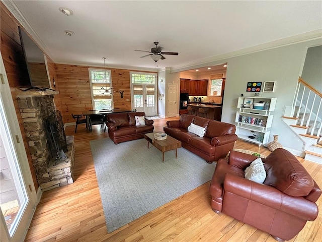 living area with light wood-style floors, ornamental molding, and stairway