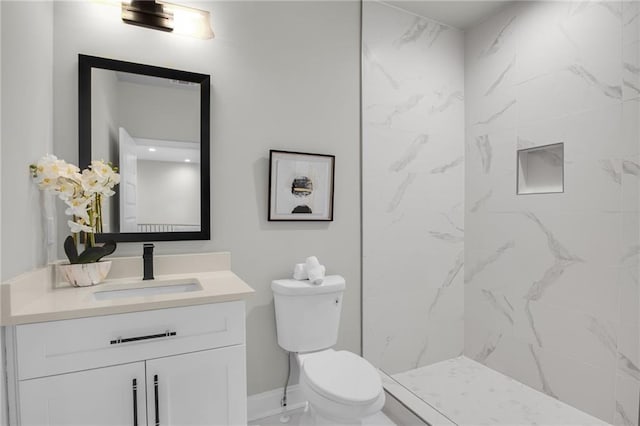 bathroom featuring marble finish floor, toilet, vanity, baseboards, and walk in shower