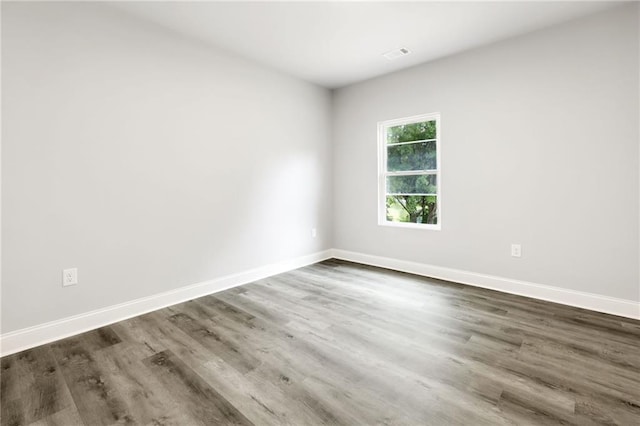 unfurnished room with dark wood-type flooring, visible vents, and baseboards