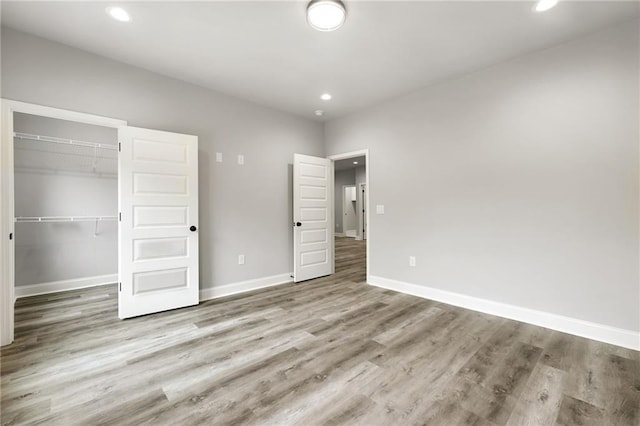 unfurnished bedroom with recessed lighting, wood finished floors, and baseboards