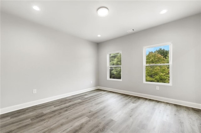 unfurnished room with recessed lighting, wood finished floors, visible vents, and baseboards