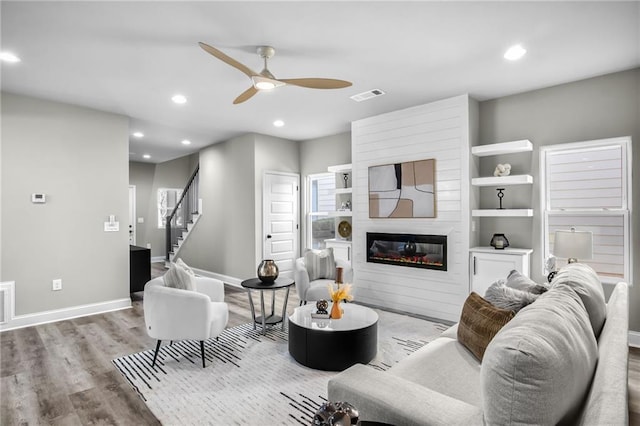 living area featuring recessed lighting, a large fireplace, visible vents, and wood finished floors