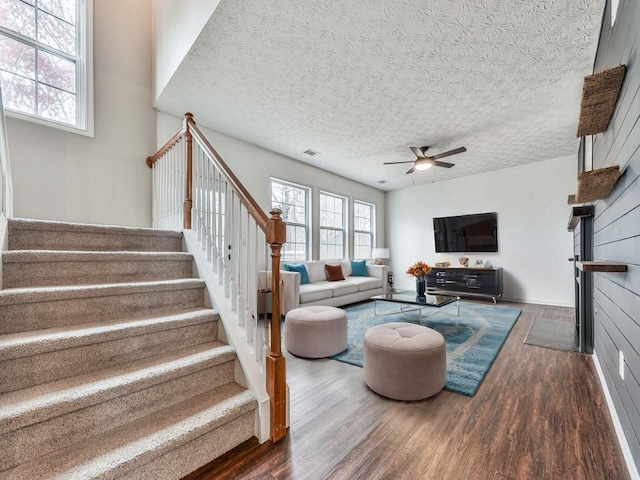 living room featuring ceiling fan, dark hardwood / wood-style flooring, and a textured ceiling