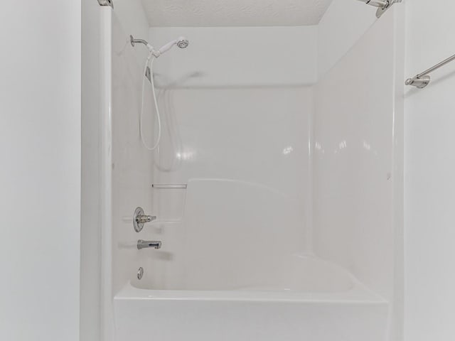 bathroom featuring a textured ceiling and bathtub / shower combination