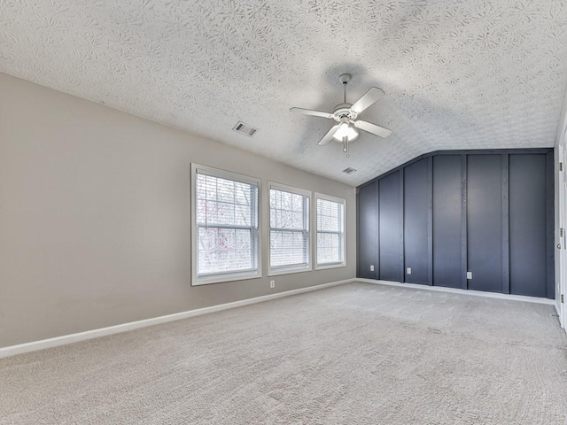 empty room featuring ceiling fan, carpet floors, a textured ceiling, and vaulted ceiling