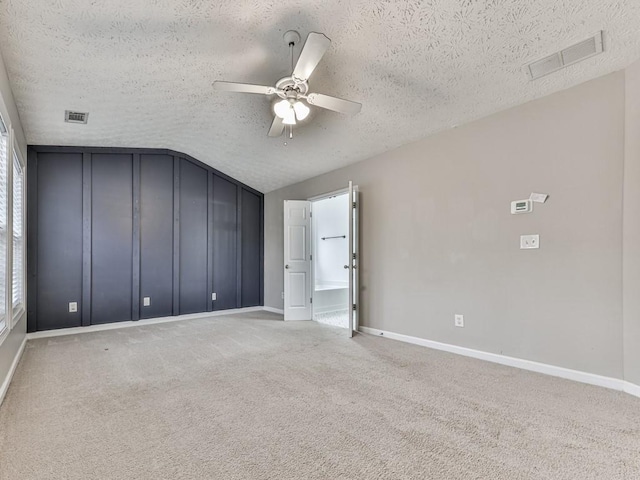 unfurnished bedroom featuring carpet flooring, a textured ceiling, vaulted ceiling, and ceiling fan