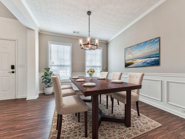 dining space with dark hardwood / wood-style flooring, a chandelier, a textured ceiling, and ornamental molding