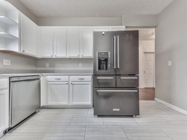 kitchen featuring light wood-type flooring, a textured ceiling, stainless steel appliances, and white cabinetry