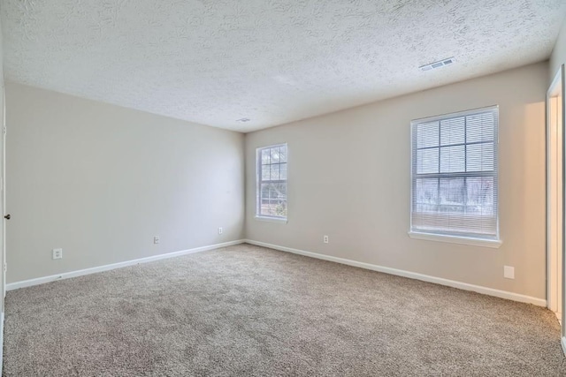 spare room featuring carpet, visible vents, and baseboards