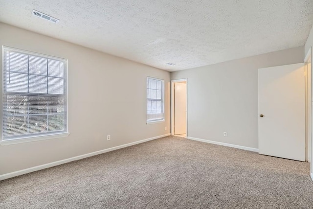 spare room featuring a healthy amount of sunlight, visible vents, baseboards, and carpet flooring