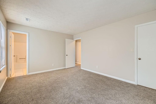 empty room featuring carpet floors, visible vents, a textured ceiling, and baseboards