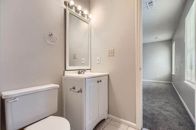 half bath with visible vents, toilet, vanity, tile patterned flooring, and baseboards