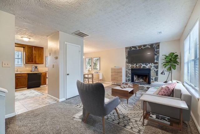 living area with visible vents, light colored carpet, a textured ceiling, and a stone fireplace