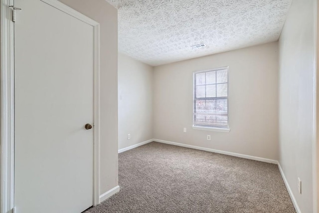 unfurnished room with carpet, visible vents, a textured ceiling, and baseboards