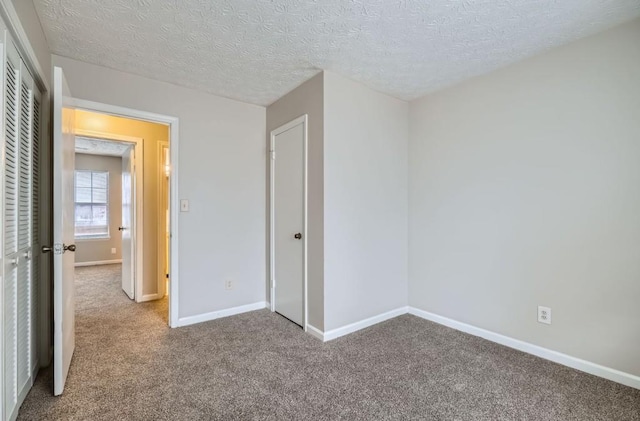 unfurnished bedroom featuring a textured ceiling, a closet, carpet, and baseboards