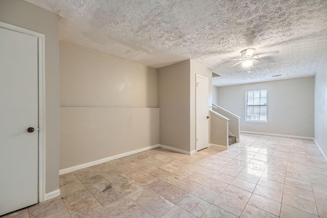 spare room featuring a textured ceiling, stairs, baseboards, and a ceiling fan