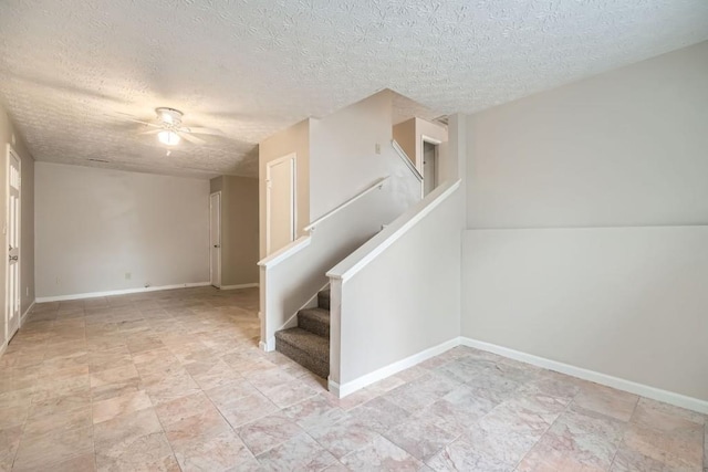 interior space featuring ceiling fan, a textured ceiling, and baseboards