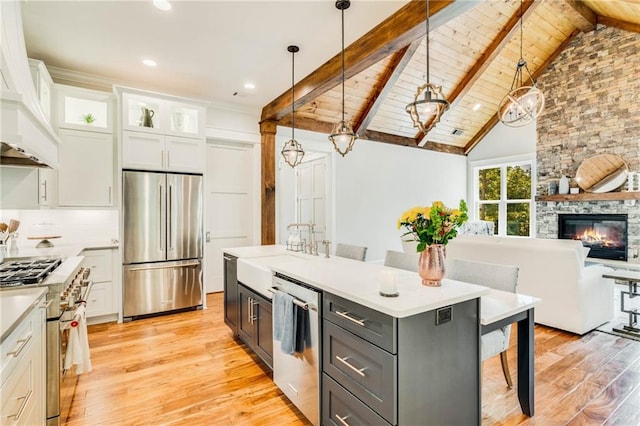 kitchen featuring decorative light fixtures, stainless steel appliances, a center island, and white cabinets