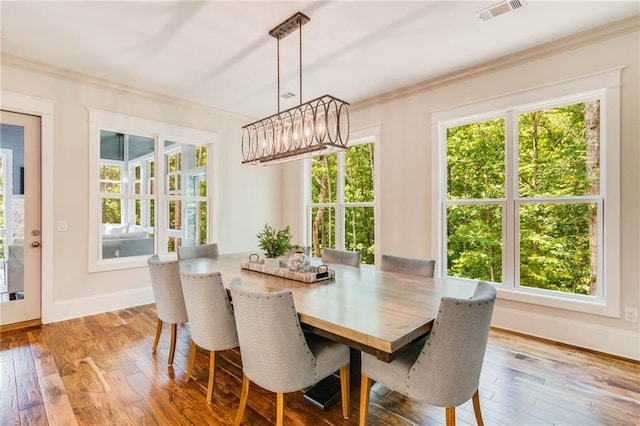 dining area with ornamental molding and light hardwood / wood-style floors