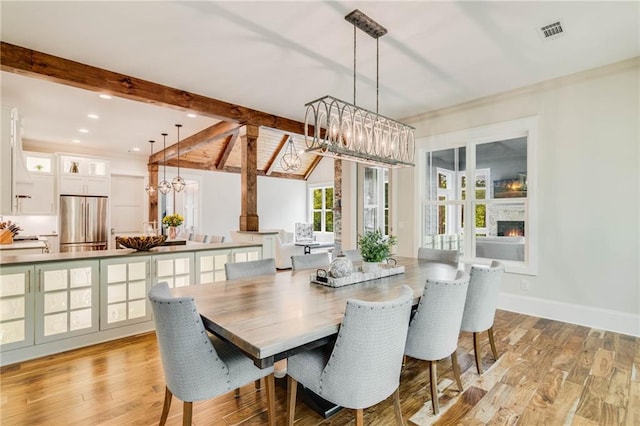 dining room with beam ceiling, a chandelier, and light hardwood / wood-style flooring