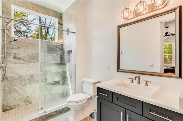 bathroom with ceiling fan, vanity, toilet, and a shower with door