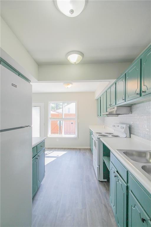 kitchen featuring decorative backsplash, white appliances, light hardwood / wood-style floors, and sink