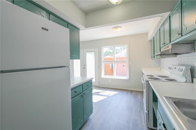 kitchen with white appliances, green cabinets, sink, hardwood / wood-style flooring, and tasteful backsplash