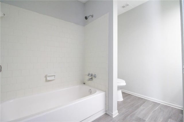 bathroom with hardwood / wood-style floors, tiled shower / bath combo, and toilet