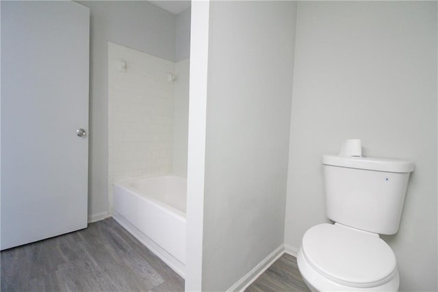 bathroom featuring hardwood / wood-style floors, toilet, and tiled shower / bath