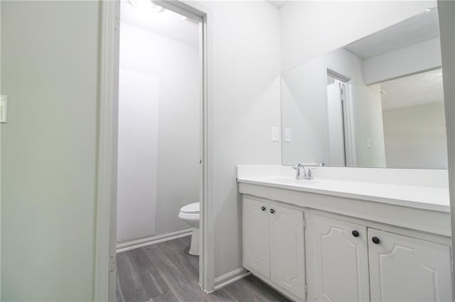 bathroom with hardwood / wood-style floors, vanity, and toilet