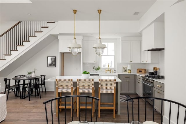 kitchen featuring white cabinetry, custom range hood, high end stove, and gray cabinetry