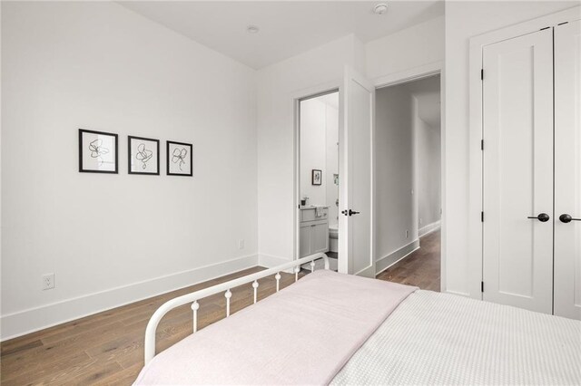 bedroom featuring a closet, dark hardwood / wood-style flooring, and ensuite bath