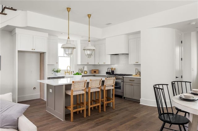 kitchen with white cabinets, a kitchen island, hanging light fixtures, and high end stainless steel range