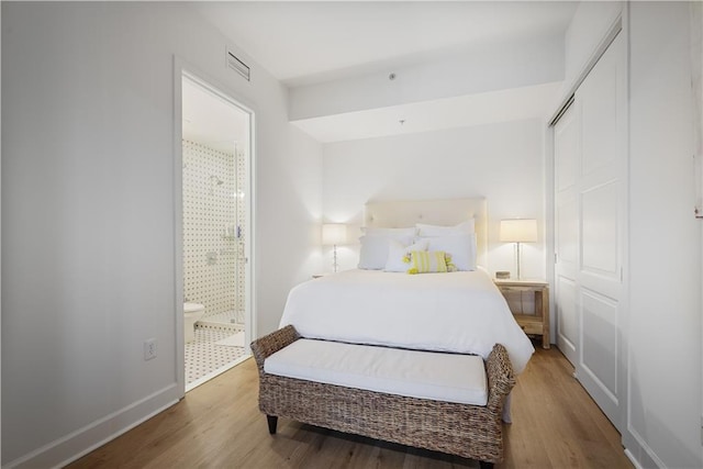 bedroom featuring connected bathroom and hardwood / wood-style flooring