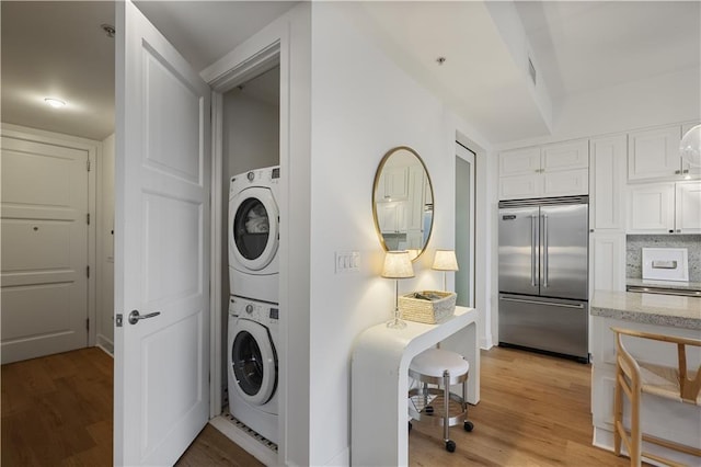 clothes washing area featuring stacked washer / dryer and light wood-type flooring