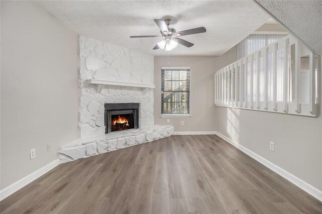 unfurnished living room with hardwood / wood-style floors, ceiling fan, a fireplace, and a textured ceiling