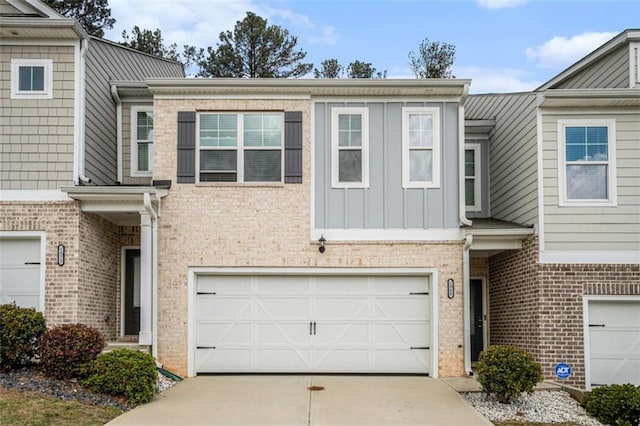 view of property with a garage, brick siding, board and batten siding, and concrete driveway