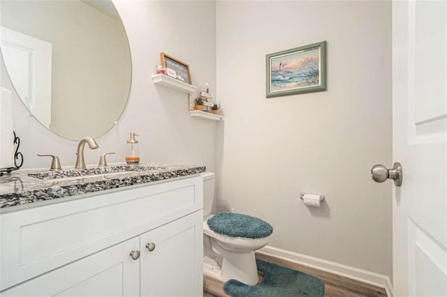 bathroom featuring toilet, wood finished floors, vanity, and baseboards