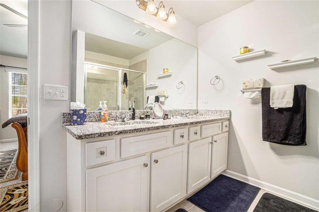 full bath with a shower stall, visible vents, a sink, double vanity, and baseboards